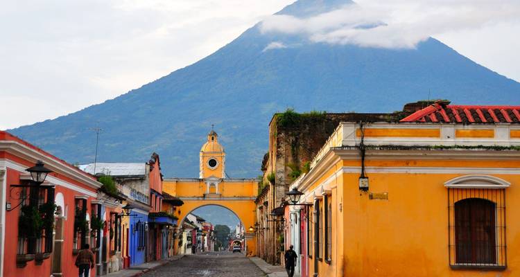 El icónico arco amarillo de la Calle Santa Catalina enmarcando un volcán en la Antigua Guatemala