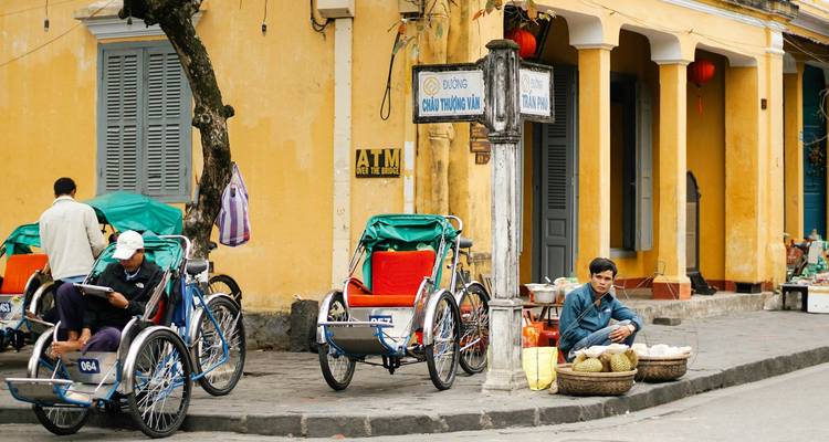 Bicycles by a yellow building with street vendor at corner.