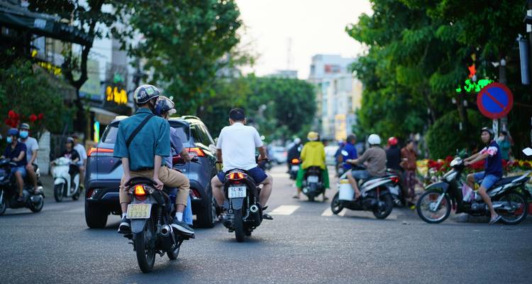 Scène de rue animée avec des motos et des voitures dans un environnement urbain.