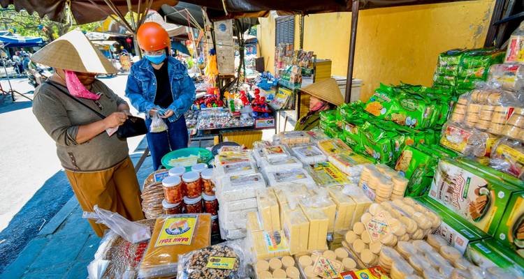 Scène de marché avec des produits colorés et des vendeurs locaux.