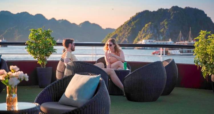 Couple se détendant sur le pont d'un bateau de croisière avec vue sur le port et les collines.