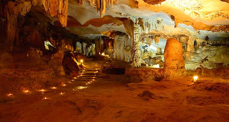 Intérieur de grotte époustouflant avec stalactites, stalagmites et éclairage chaleureux.