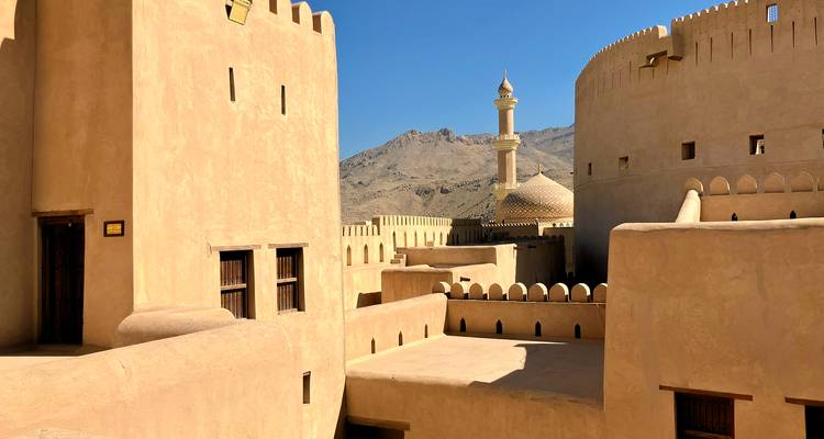 Historische Wüstenfestung mit Minarett und gezinnten Mauern unter klarem blauen Himmel