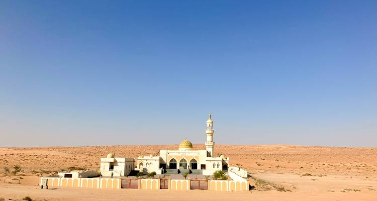 Isolierte Moschee mit goldener Kuppel, die einsam in einer Wüstenlandschaft steht