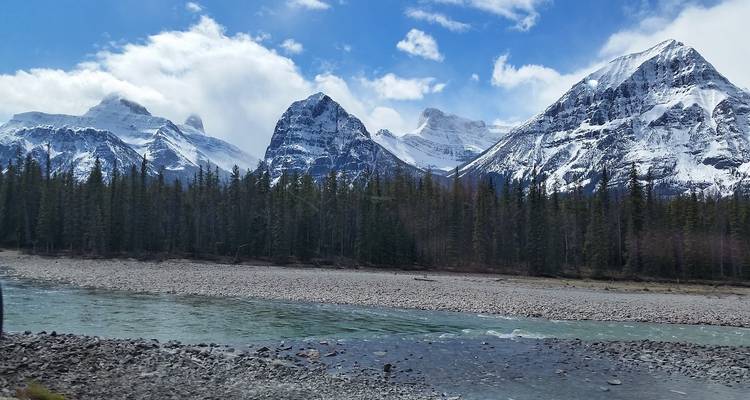 Schneebedeckte Berge mit einem Fluss im Vordergrund.