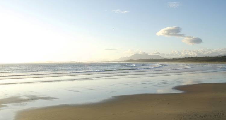 Malerischer Strand mit sanften Wellen unter einem hellen Himmel.