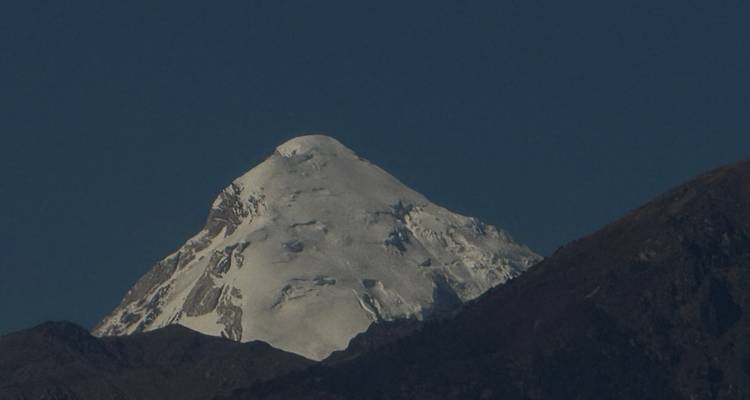 Pic enneigé contre un ciel crépusculaire bleu profond.