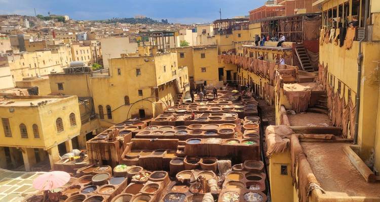 Blick über Fès-Gerberei-Bottiche gefüllt mit bunten Farbstoffen, umgeben von mehrstöckigen gelben Gebäuden.