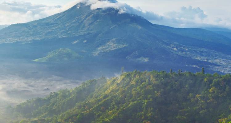 Las crestas iluminadas por el sol y los valles brumosos rodean el cono volcánico del Monte Batur.