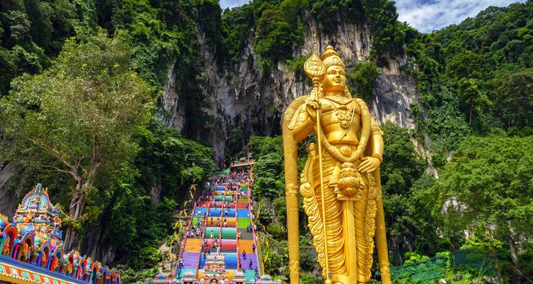 Gouden standbeeld bij de ingang van kleurrijke tempeltreden.
