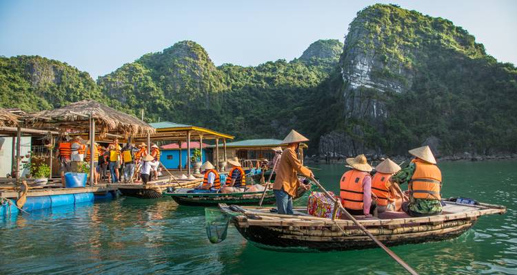 Touristes dans des bateaux entourés de formations calcaires pittoresques.