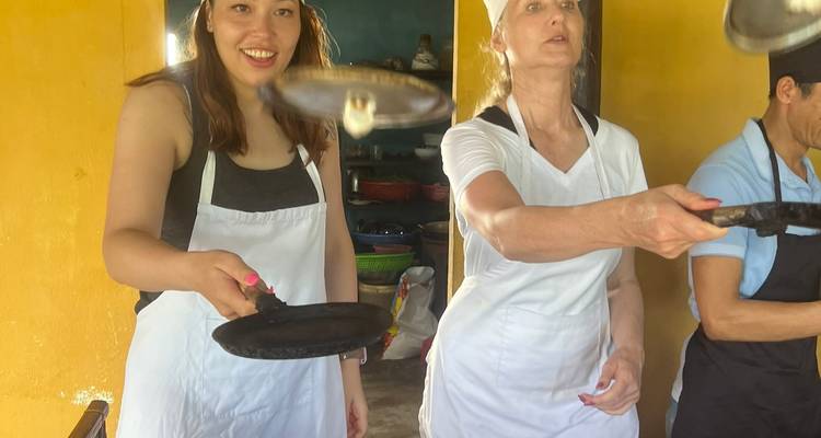 Les participants d'un cours de cuisine retournent de petites crêpes dans une cuisine jaune vif.