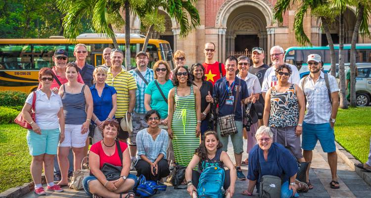 Touristes souriants posant pour une photo de groupe dans un lieu pittoresque en plein air.