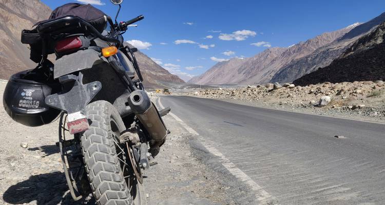Geparkeerde motorfiets op een weg in een bergachtig gebied.