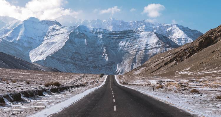 Sneeuwbedekte weg die verdwijnt in de verre bergen.