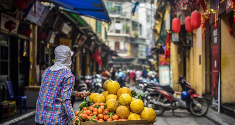 Een straatverkoper met levendige sinaasappels in een drukke straat in Hanoi.