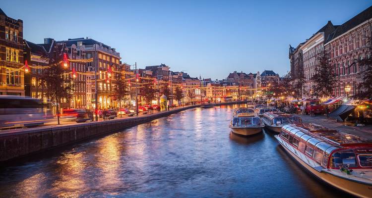 Canal en una ciudad con edificios iluminados y barcos por la noche.