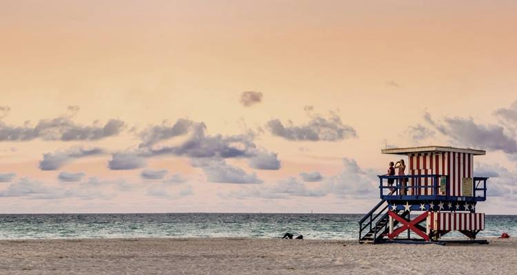Beach scene with a lifeguard tower and pastel sky.