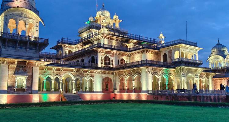 Das Albert Hall Museum in Jaipur, beleuchtet mit mehrfarbigen Lichtern vor einem tief blauen Dämmerungshimmel.