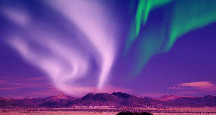 Heldere aurora die over paarse nachtlucht boven IJslandse bergen scheert