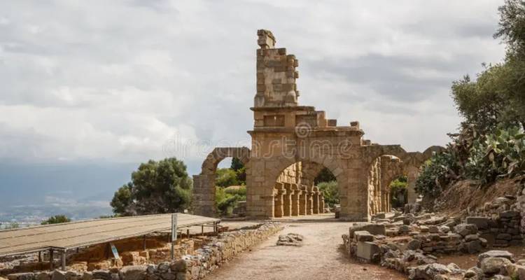 Stenen bogen en zuilen van oude ruïnes kijken uit over een ruig Siciliaans landschap.