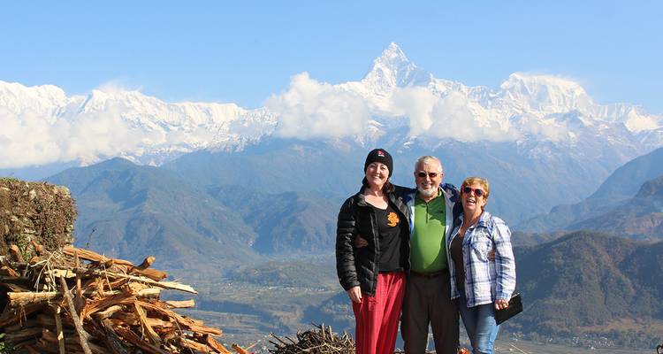 Drie mensen poseren voor bergen met besneeuwde toppen.