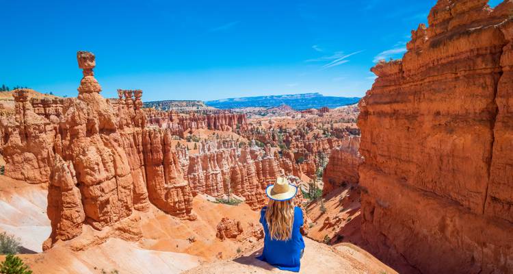 A person sitting on the edge of Bryce Canyon, surrounded by stunning red rock formations.