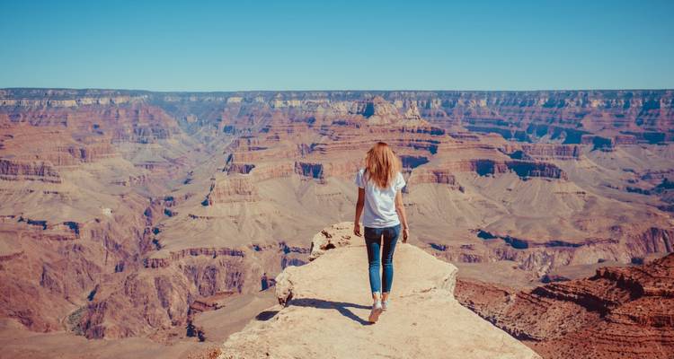Woman standing on the edge of Grand Canyon with distant view.
