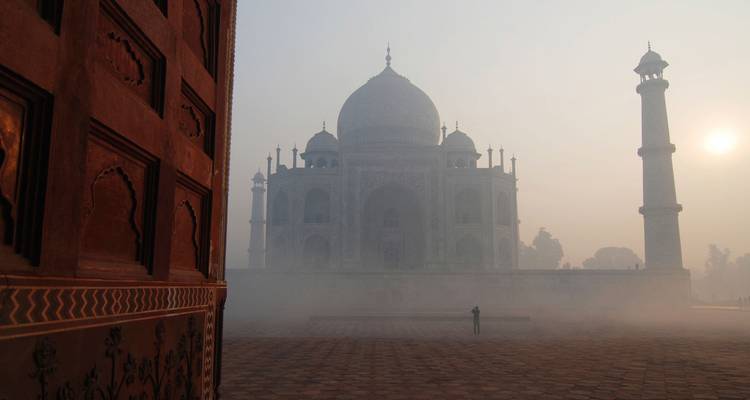 La niebla envuelve el Taj Mahal al amanecer mientras una figura solitaria contempla su grandiosidad.