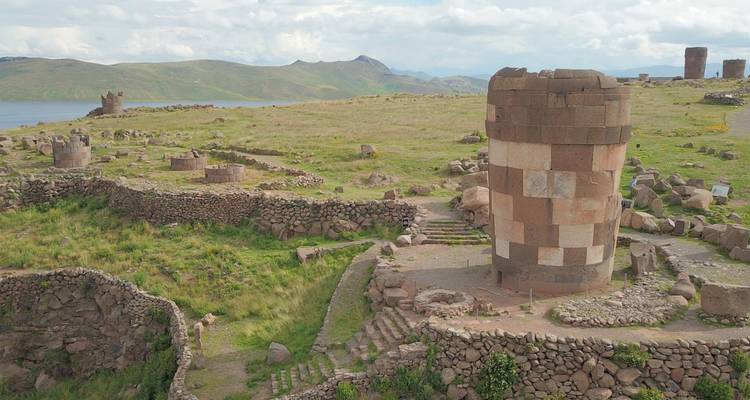Aerial panorama of cylindrical chullpas and stone walls scattered across green peninsulas jutting into Lake Umayo.