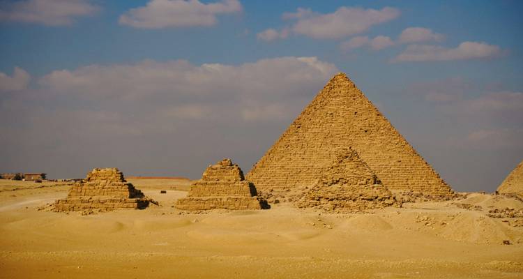 Tres pirámides en el desierto bajo un cielo parcialmente nublado.