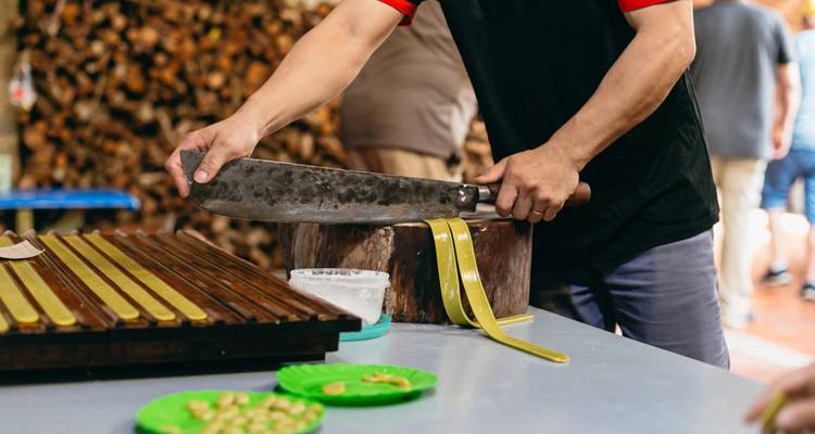 Close-up of a craftsman slicing nougat candy with a large blade on a wooden block.