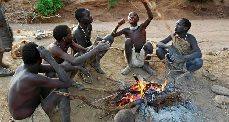 Gruppe von Menschen um ein Lagerfeuer in ländlicher Umgebung.