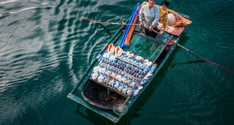 Couple selling goods on a small boat in Halong Bay.