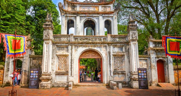 Historic gate entrance with people entering and colorful flags.