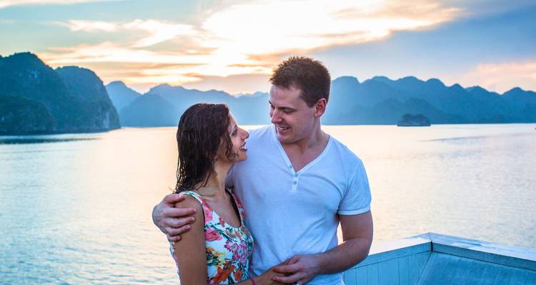 Couple enjoying a romantic moment on a boat at sunset.