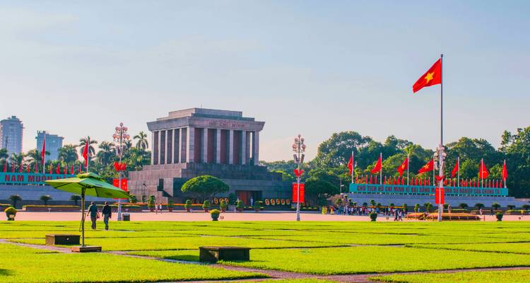Ho Chi Minh Mausoleum with a Vietnamese flag in the foreground.