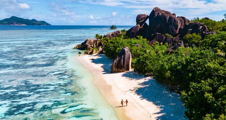 Couple walking on a beach with granite boulders.