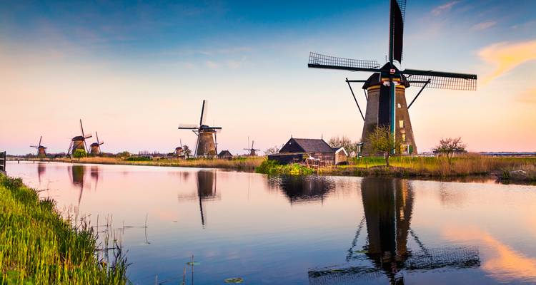 Windmills along a canal at sunset.