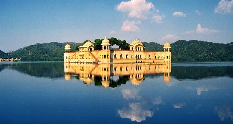 Jal Mahal spiegelt sich in einem See unter klarem Himmel.