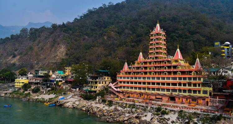 Iconische tempel aan een rivier met rotsachtige heuvels op de achtergrond.