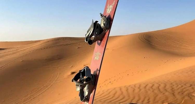Snowboard stuck in sand dunes of the desert.
