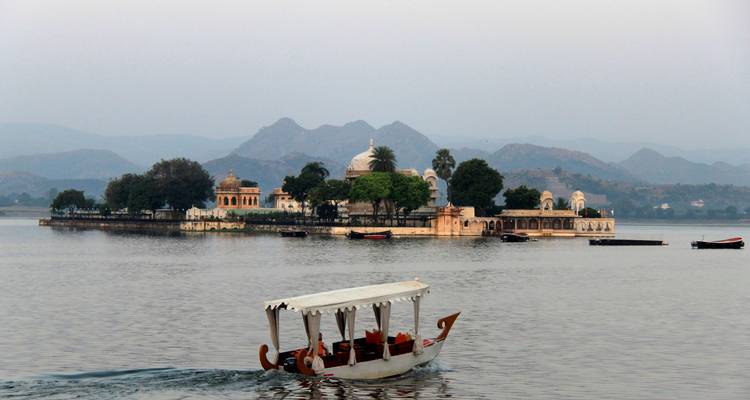 Een boot op een meer met een eilandpaleis op de achtergrond bij dageraad.