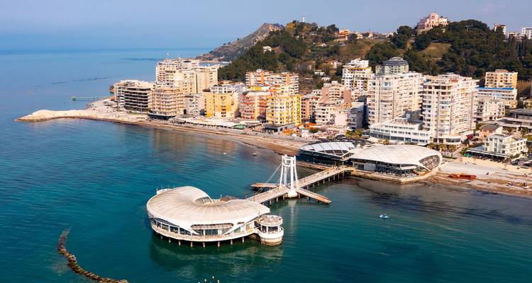 Vue aérienne de la façade maritime de Durrës mettant en évidence la jetée circulaire et les hôtels balnéaires modernes.