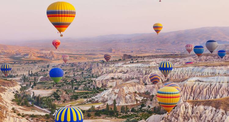 Dageraadhemel gevuld met kleurrijke luchtballonnen die boven Cappadocië's maanlandschap zweven.