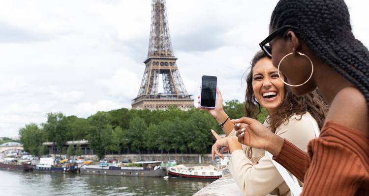 Zwei Frauen lachen mit dem Eiffelturm im Hintergrund.