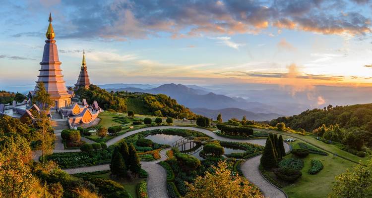 Las pagodas gemelas de Doi Inthanon se elevan sobre jardines cuidados y el paisaje montañoso y brumoso al amanecer.