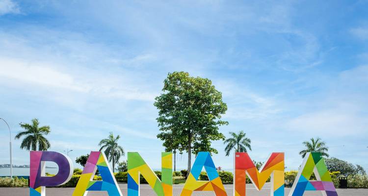 Colorido letrero de PANAMA con palmeras bajo un brillante cielo tropical azul.
