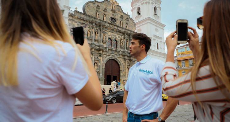 Los viajeros fotografían a su guía frente a una catedral blanca ornamentada.