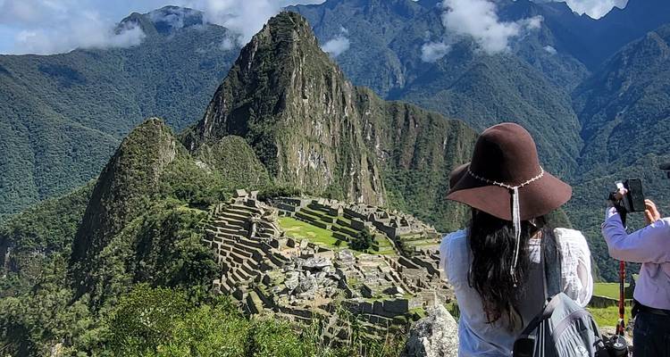 Panorama classique des ruines du Machu Picchu avec des touristes prenant des photos sur fond de pics andins.